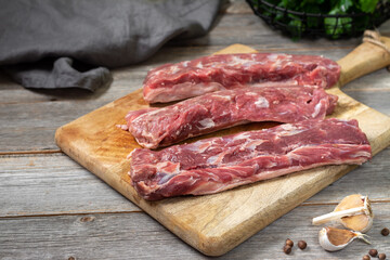 Lamb meat. A young lamb on a wooden Board on a gray wooden kitchen table. Lamb meat and cooking ingredients. The view from the top