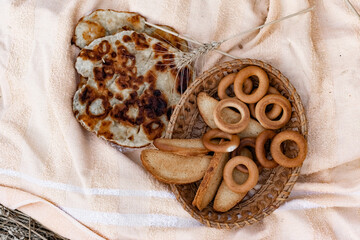 An edible composition of flour baking in a basket on a bedspread, among Golden ears of barley in nature. A big fat donut, vanilla crackers and bagels round
