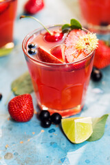 Red drink in glass with slices of apple and strawberry