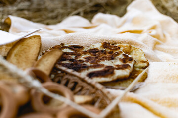 An edible composition of flour baking in a basket on a bedspread, among Golden ears of barley in nature. A big fat donut, vanilla crackers and bagels round