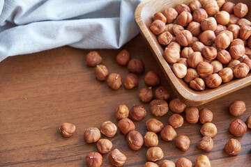 Hazelnut kernels and whole hazelnuts on old brown table, selective focus.