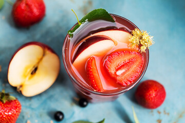 Summer cocktail with strawberry, flower and apple