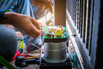 A Technician assembling motor system and testing motor automatic gate by screwdriver home security system. - obrazy, fototapety, plakaty
