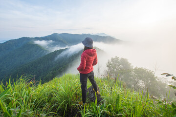 Naklejka premium rear of happy woman stand on top mountain looking view with mist and cloud at morning light Soft focus.