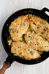 Homemade Italian Chicken Piccata in a cast iron pan, top view. Overhead, from above, flat lay.