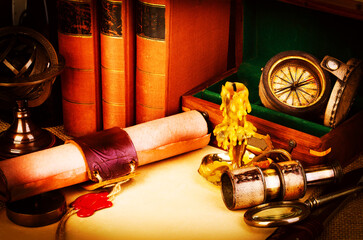 Old books, feather pen and ink bottle, old scroll with red wax seal, vintage compass. Adventure stories background.