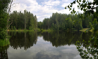 A small forest lake for fishing and tourism with tents .