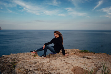 Naklejka na ściany i meble Woman above cold sea on cliff alone. Travel Lifestyle concept