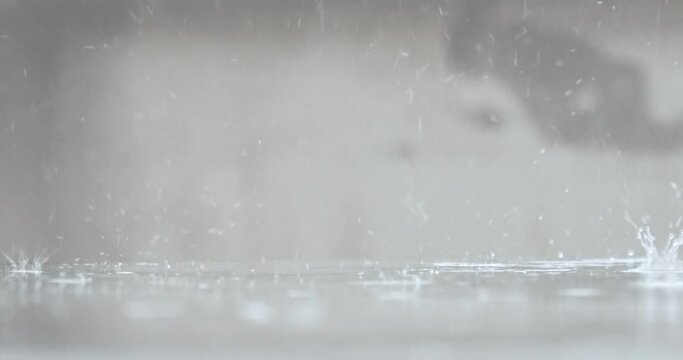 Raindrops Fall To The Floor In Slow Motion Over A Blurred White Background