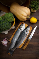 Raw sea bass, pumpkin, broccoli, lemon, thyme and garlic on a table