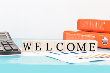 WELCOME text on wooden building blocks on top of office desk. Business finance meeting or workshop...