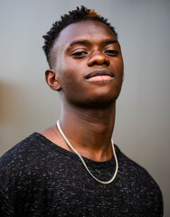 Obraz premium A shallow focus shot of a young black male on a grey wall background with a great smile