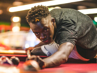 Shallow focus shot of a young black male in a billiards playroom - obrazy, fototapety, plakaty