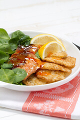 Baked coho salmon, rice pancakes, lemon and young spinach leaves