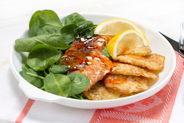 Baked coho salmon, rice pancakes, lemon and young spinach leaves