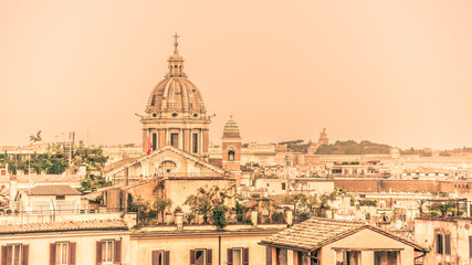 Fototapeta na wymiar Rome skyline with old colorful houses and rooftop terraces on sunny day. Dome of San Carlo al Corso basilica on the background. Rome, Italy