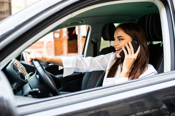 Young woman making a phone call while driving a car to work.