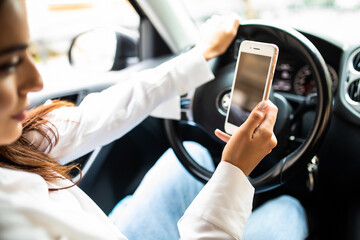 Business woman sitting in car and using her smartphone from back. Mockup image with female driver and phone screen