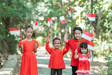 four little girls smile when they stand wearing red and white attributes while carrying the...