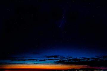 The comet Neowise appears in the sky, close to the horizon.