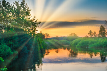 Fototapeta na wymiar Lake water sunset and sun rays on nature landscape with sunset sky