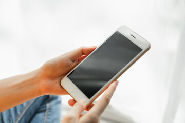 Woman hand holding smartphone and touching blank screen. Mockup of advertisement.