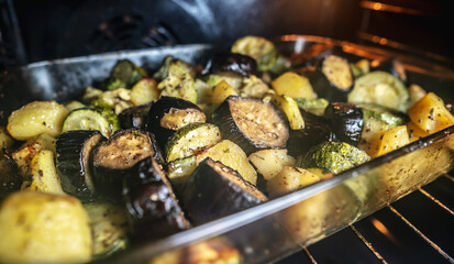 Hot delicious vegetables in a glass dish in the oven. Concept of healthy and seasonal dishes of fast preparation