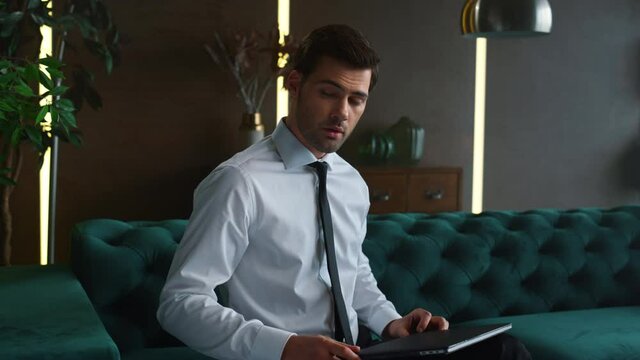 Businessman closing laptop after work in office. Worker sitting on sofa