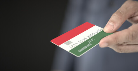 Man offers credit card with printed flag of Hungary. Fictional numbers