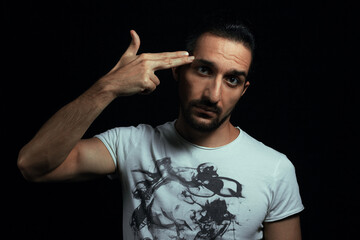 Hand in the form of a pistol. The guy puts his hand to his head in the shape of a pistol. Photo on black background
