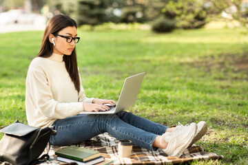 Asian woman using laptop, working in the park