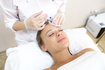 The beautician makes the patient injections and the forehead area during the procedure of mesotherapy and botox