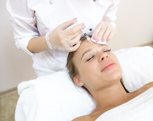 Obraz na płótnie Canvas The beautician makes the patient injections and the forehead area during the procedure of mesotherapy and botox