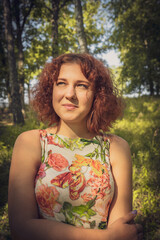 red-haired curly-haired girl in a summer dress posing in the village . High quality photo