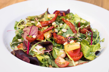 Salad with dried tomatoes and duck, exotic salad in a plate close-up