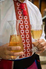 A man in a national Ukrainian shirt holds a decanter of wine in his hands