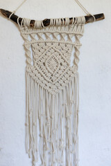 Macrame wall decor made of natural cotton rope of milky color on a white background