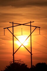 Power lines silhouettes with a Kansas colorful Sunset with cloud's and the Sun out in the country. West of Sterling Kansas USA that's bright and colorful.