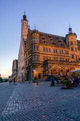 Naklejka premium people enjoy a beautiful summer evening in the street cafes in the market square of Rothenburg