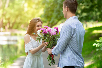 Beautiful woman smelling bouquet of flowers given by her boyfriend at park