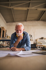 Elderly craftsman is reading blueprint