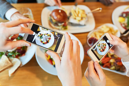 Hands with smartphones take pictures of food