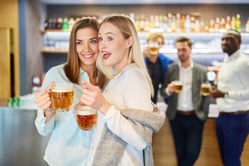 Girlfriends together drink beer in a pub