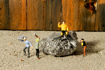 Miniatur Bergarbeiter bauen einen Stein aus Silber ab