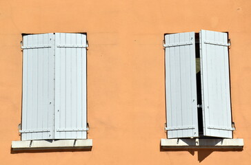 Wei&szlig;e Fensterl&auml;den in einer orangen Hausfassade