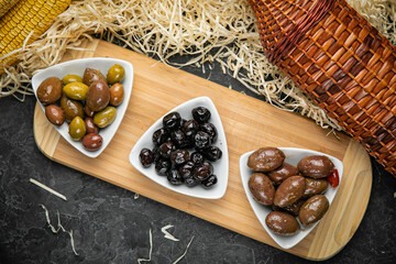 different types of olives on a dark concrete