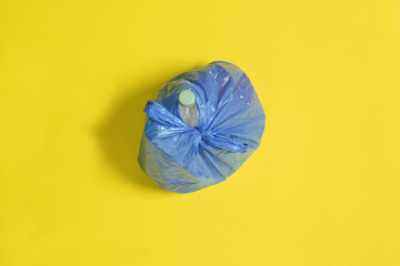 top view of a closed blue garbage bag on yellow background