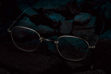 silberne Brille auf schwarzer Holzkohle mit blauem Licht