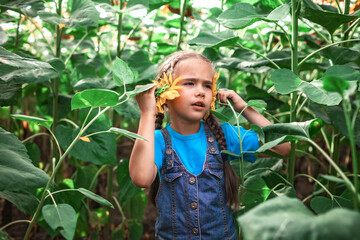 Local travel. Kid imitating listening music with sunflower in the field, outdoor lifestyle