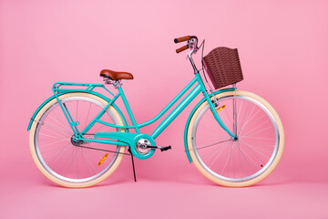 Photo of woman retro vintage bicycle used for town transportation with brown basked isolated over pink color background